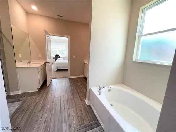 a large white tub sitting in a bathroom next to a window