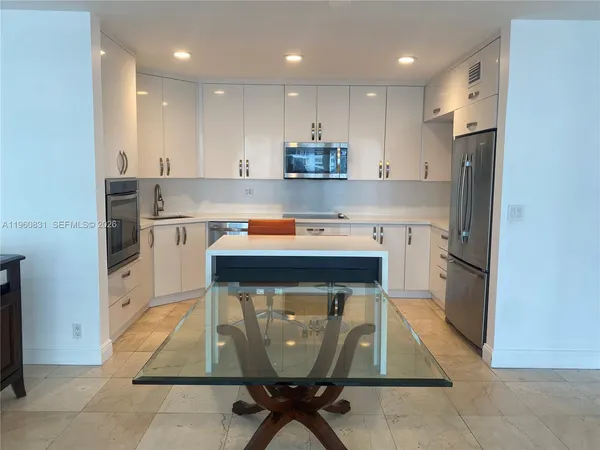 a kitchen with stainless steel appliances granite countertop a table chairs sink and cabinets