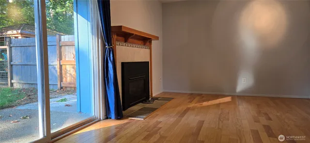 a view of an empty room with wooden floor and a fireplace
