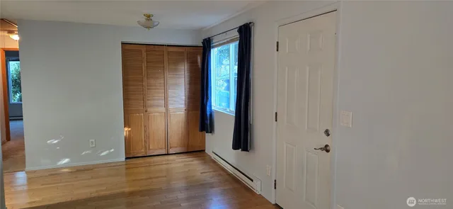 a view of an empty room with wooden floor and a window
