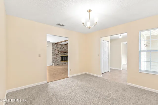 an empty room with chandelier fan and windows