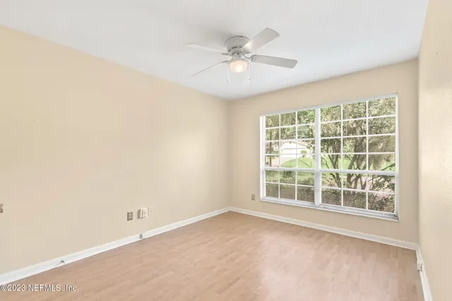 an empty room with windows and fan