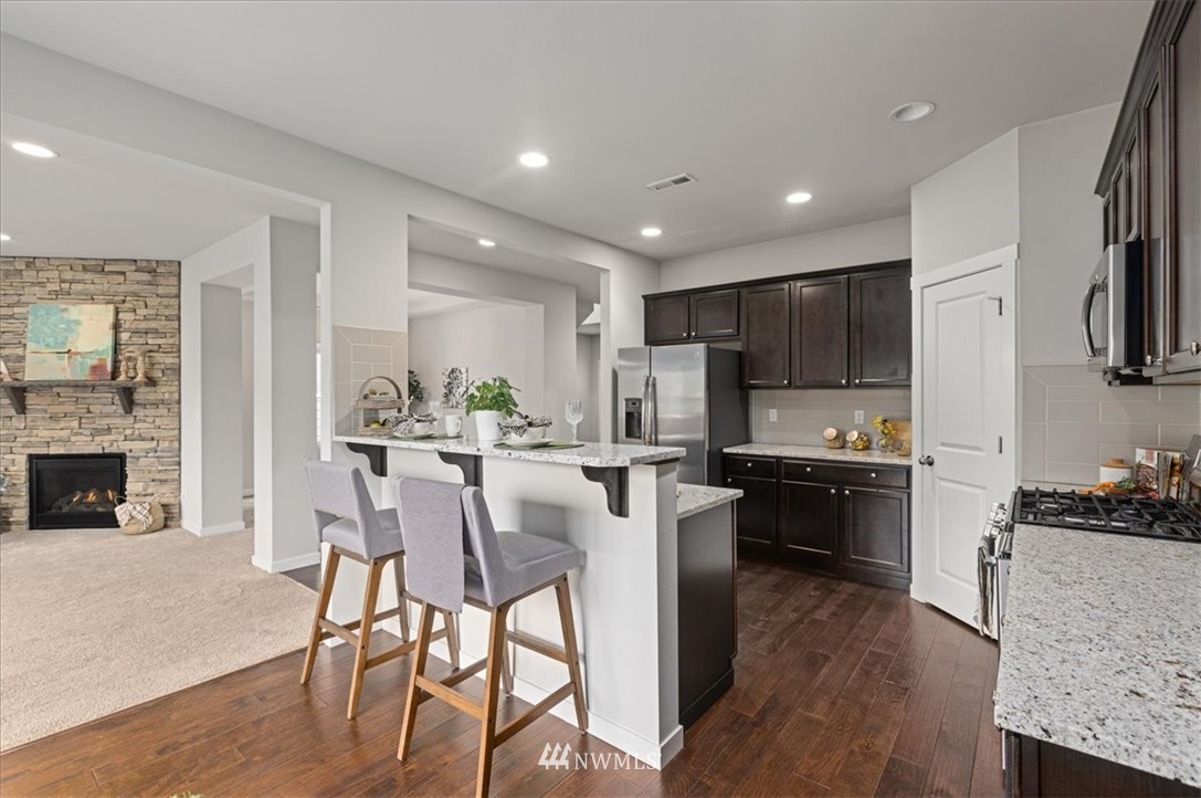 26 157th Lane Southeast Bothell, WA 98012 - Photo 7 of 37 a kitchen with stainless steel appliances kitchen island granite countertop a stove top oven a refrigerator a sink and a dining table with wooden floor