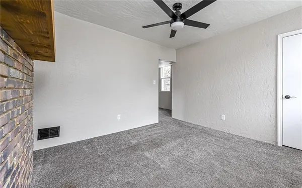 an empty room with a ceiling fan and carpet