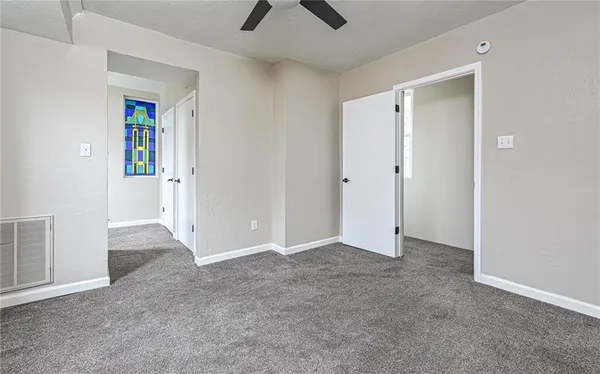 an empty room with closet and a ceiling fan