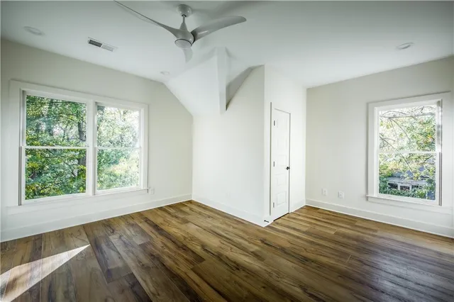 a view of a room with wooden floor ceiling fan and windows