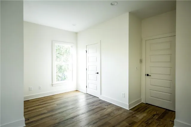 an empty room with wooden floor cabinet and windows