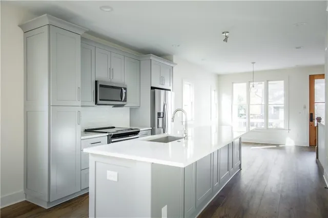 a kitchen with sink a microwave and wooden floor