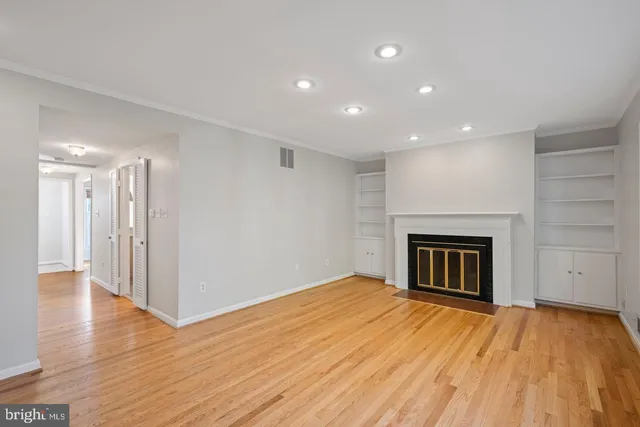 a view of an empty room with wooden floor fireplace and a window