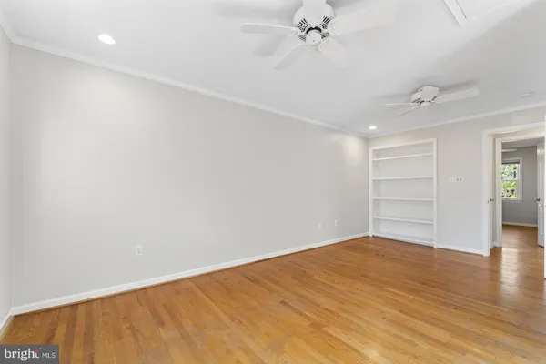 an empty room with wooden floor closet and windows