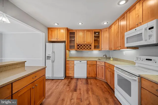 a kitchen with stainless steel appliances granite countertop a refrigerator a sink dishwasher a stove and white countertops with wooden floor