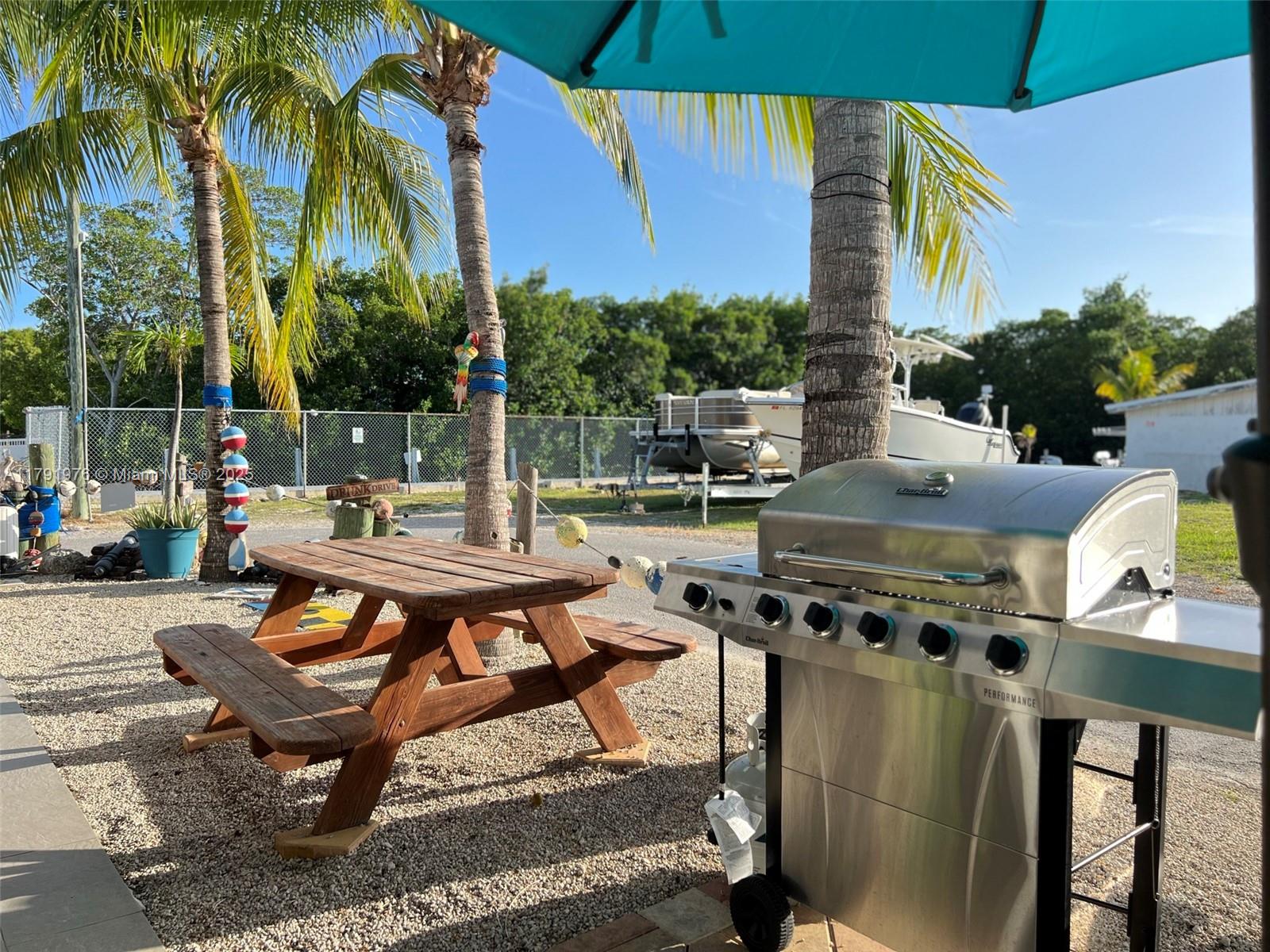 325 Calusa Street Key Largo, FL 33037 - Photo 10 of 48 a backyard of a house with barbeque oven table and chairs