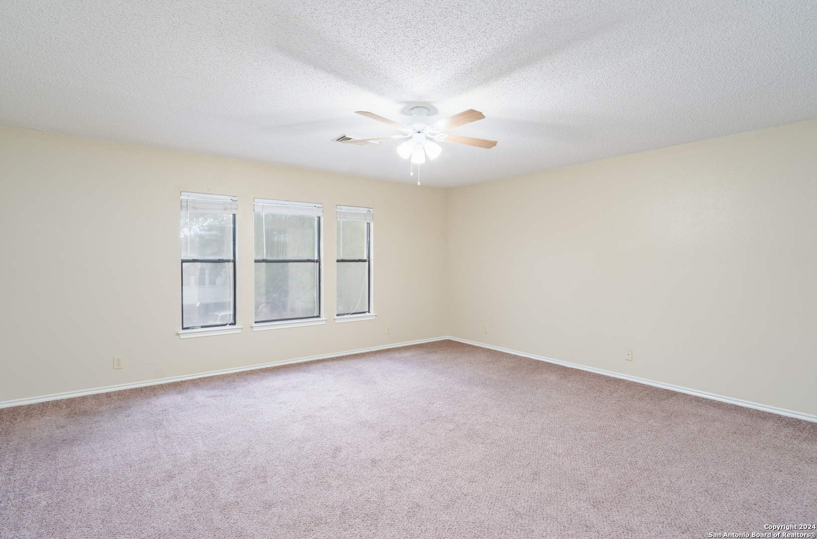 9243 Windward Trace San Antonio, TX 78254 - Photo 11 of 24 an empty room with chandelier fan and windows