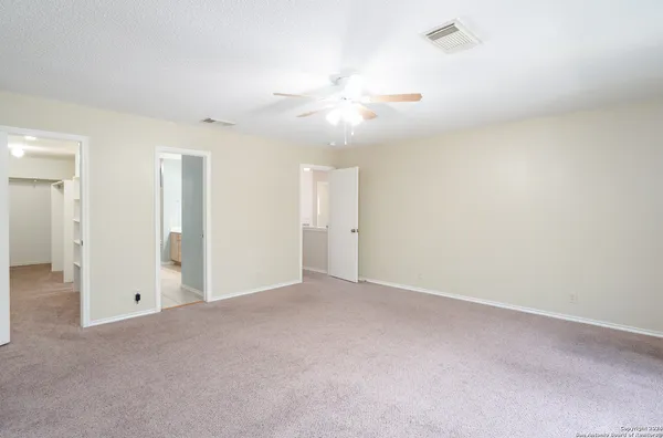 an empty room with closet and a ceiling fan