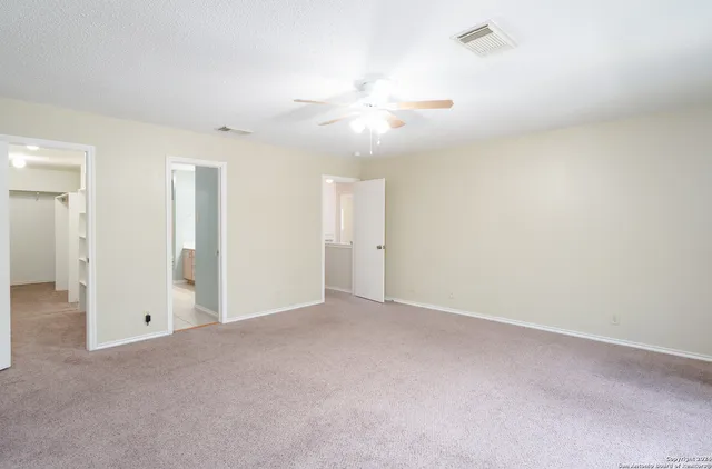 an empty room with closet and a ceiling fan