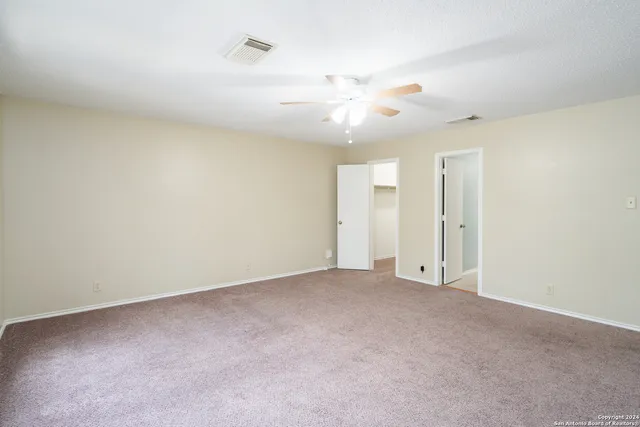 an empty room with a ceiling fan and a fan