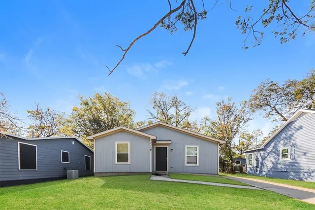 a view of a yard in front of a house with plants and large tree