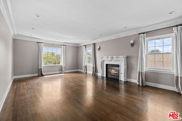 an empty room with wooden floor fireplace and windows