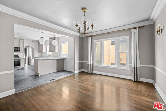 a view of an empty room with kitchen and window