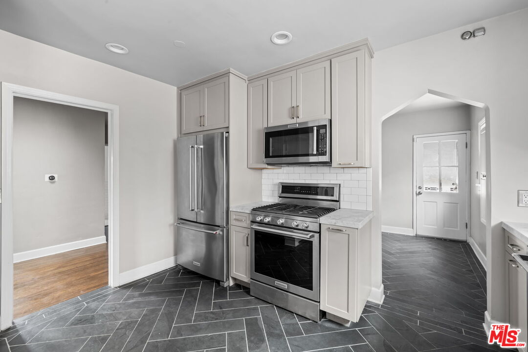 1307 South Rimpau Boulevard Los Angeles, CA 90019 - Photo 6 of 22 a kitchen with stainless steel appliances a stove a refrigerator and a microwave