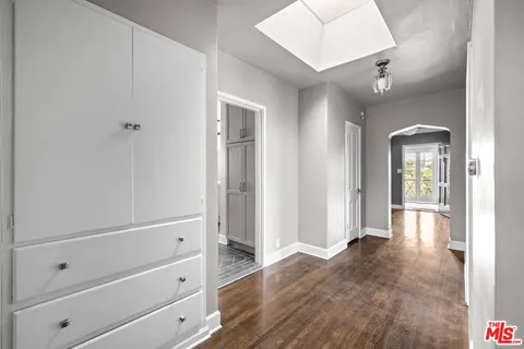 a view of a hallway with wooden floor and cabinet