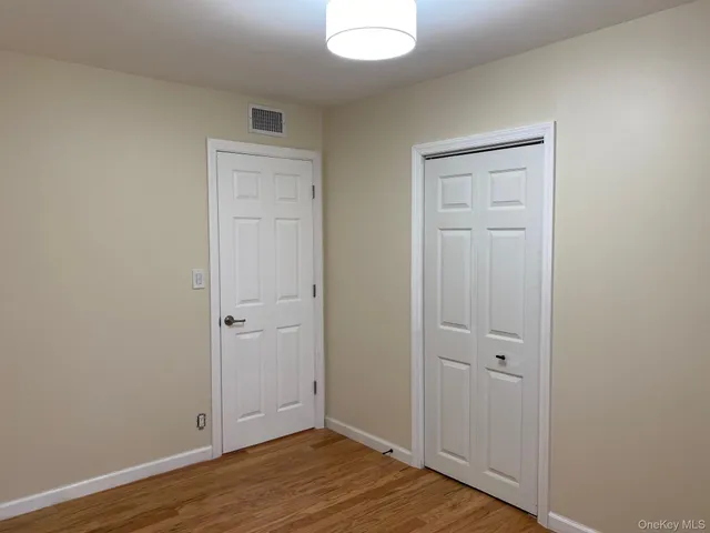 an empty room with wooden floor and closet area