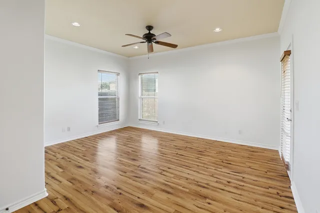 a view of empty room with wooden floor and ceiling fan
