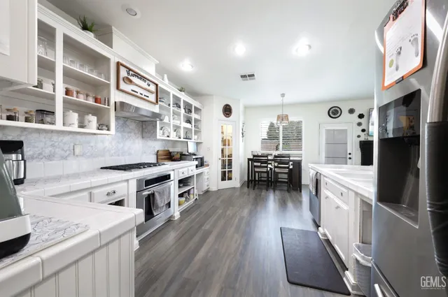a large kitchen with stainless steel appliances granite countertop a lot of counter space and wooden floors