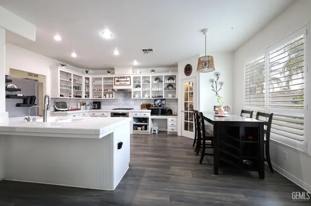 a kitchen with stainless steel appliances granite countertop a table chairs and a refrigerator