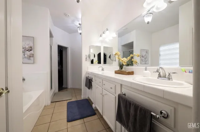 a spacious bathroom with a double vanity sink a mirror and a shower