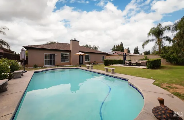 a view of a house with swimming pool lawn chairs and a yard