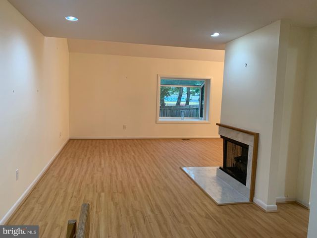 an empty room with wooden floor a fireplace and windows
