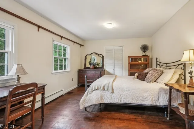 a bedroom with a bed a table and chair with the large mirror