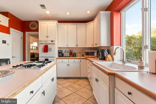 a kitchen with kitchen island granite countertop a sink appliances cabinets and a large window
