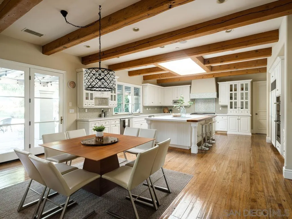 18072 Rancho La Cima Corte Rancho Santa Fe, CA 92067 - Photo 11 of 32 a dining room with stainless steel appliances kitchen island granite countertop a table chairs and a wooden floor
