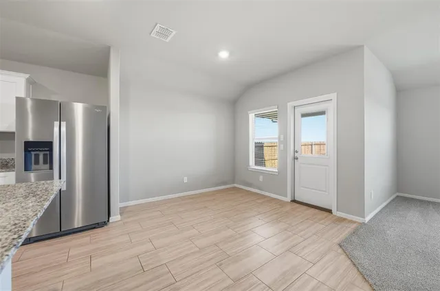 a large white kitchen with a refrigerator a stove top oven and white cabinets