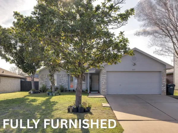 a view of a house with a yard garage and large tree