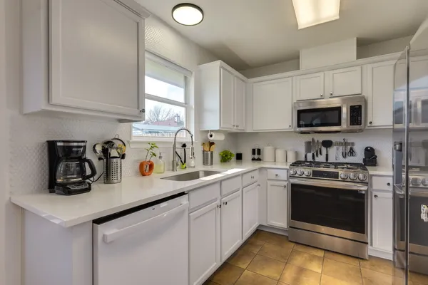 a kitchen with stainless steel appliances granite countertop a sink a stove a microwave a refrigerator a counter space and cabinets