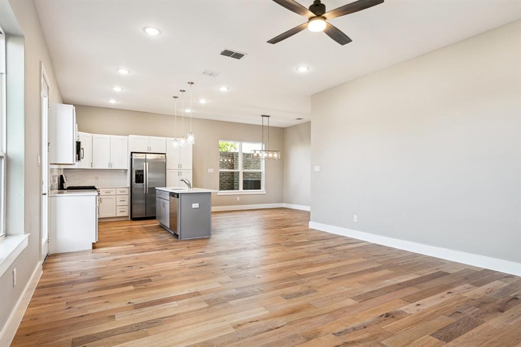 1711 Paytyn Drive Allen, TX 75013 - Photo 9 of 37 Kitchen featuring ceiling fan with notable chandelier, white cabinets, hanging light fixtures, stainless steel fridge with ice dispenser, and a center island with sink
