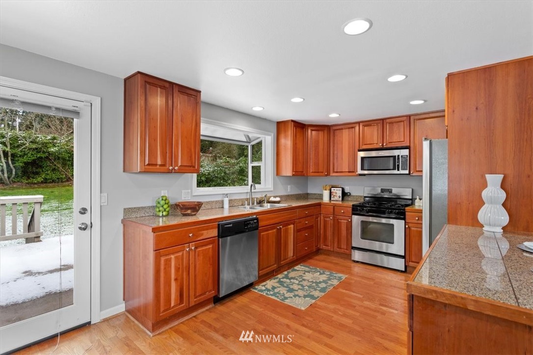 17526 Southeast 135th Street Renton, WA 98059 - Photo 10 of 37 a kitchen with stainless steel appliances granite countertop wooden cabinets a stove top oven a sink and dishwasher