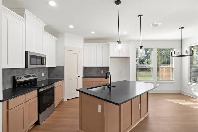 a kitchen with stainless steel appliances granite countertop a sink a stove and a refrigerator