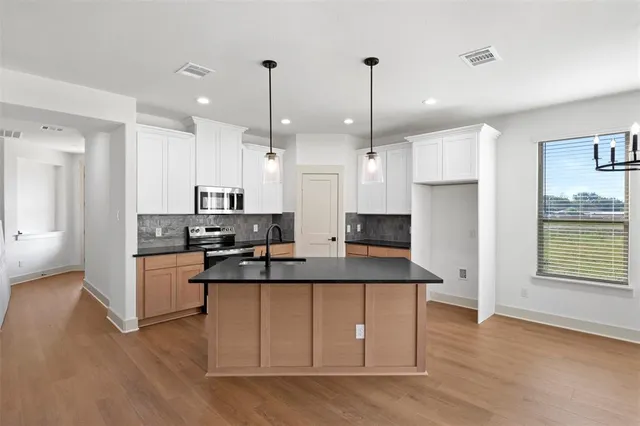 a kitchen with stainless steel appliances granite countertop a sink a stove and a wooden floors
