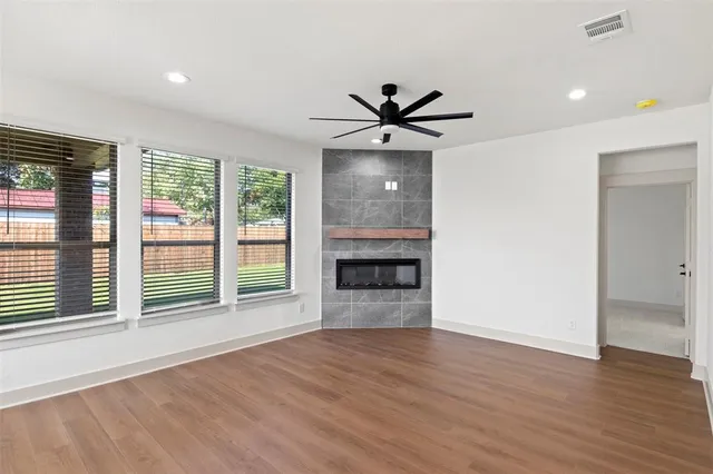 a view of an empty room with a window and wooden floor