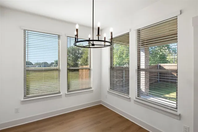 a view of empty room with wooden floor and windows