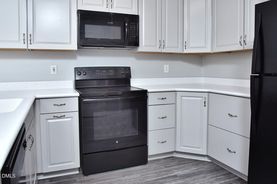 6 Justin Court Durham, NC 27705 - Photo 8 of 22 a kitchen with white cabinets and a stove with wooden floor