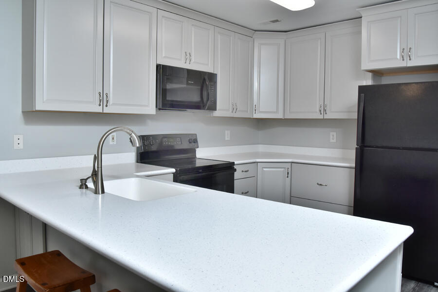 6 Justin Court Durham, NC 27705 - Photo 9 of 22 a kitchen with stainless steel appliances a refrigerator sink and cabinets