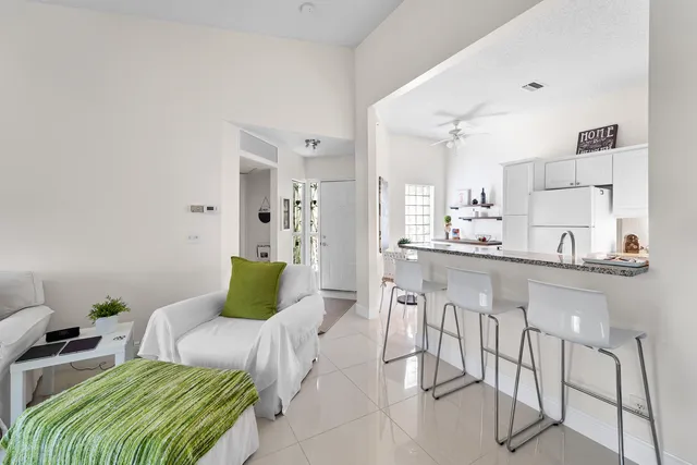 a living room with furniture kitchen view and a large window