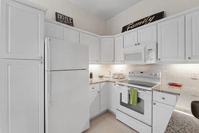 a kitchen with a refrigerator and white cabinets