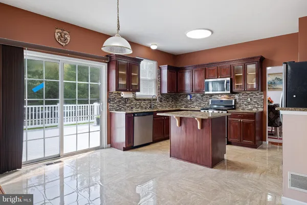 a kitchen with stainless steel appliances granite countertop a stove a sink dishwasher a refrigerator and a oven with large windows