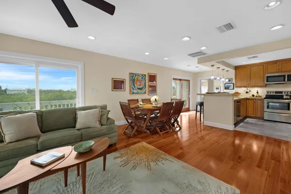 a kitchen with stainless steel appliances granite countertop a stove a refrigerator a kitchen island a dining table and chairs with wooden floor